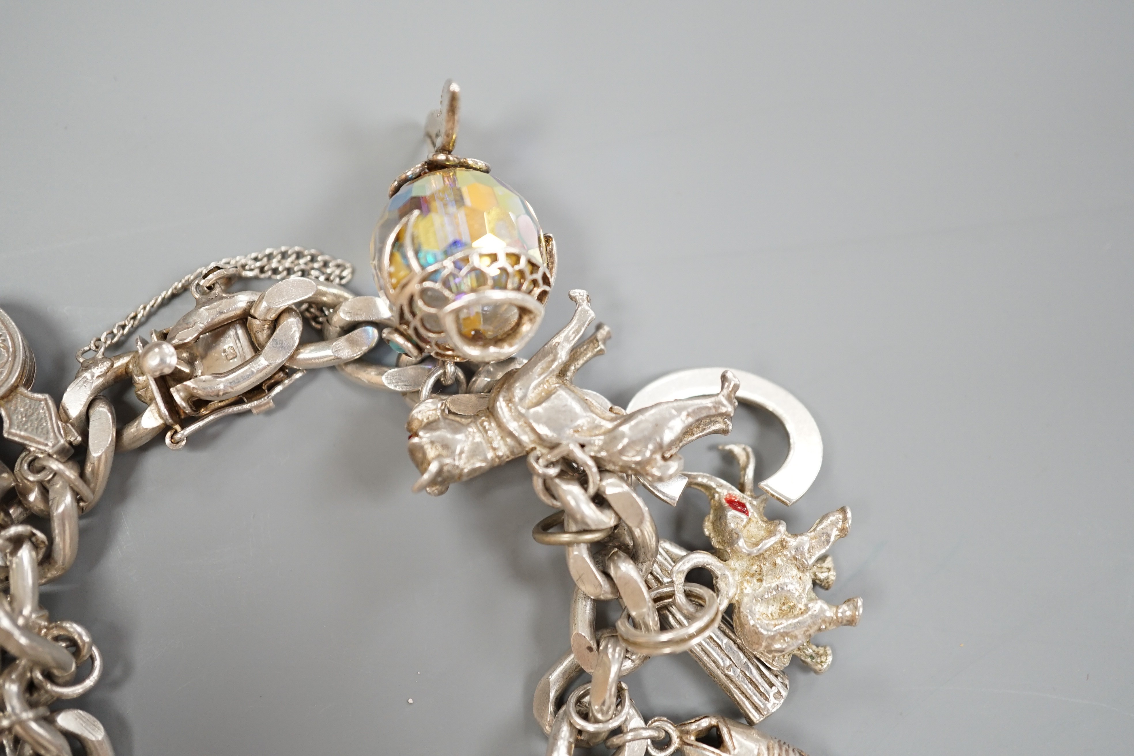 A silver charm bracelet, hung with sixteen assorted charms, gross weight 107.6 grams.